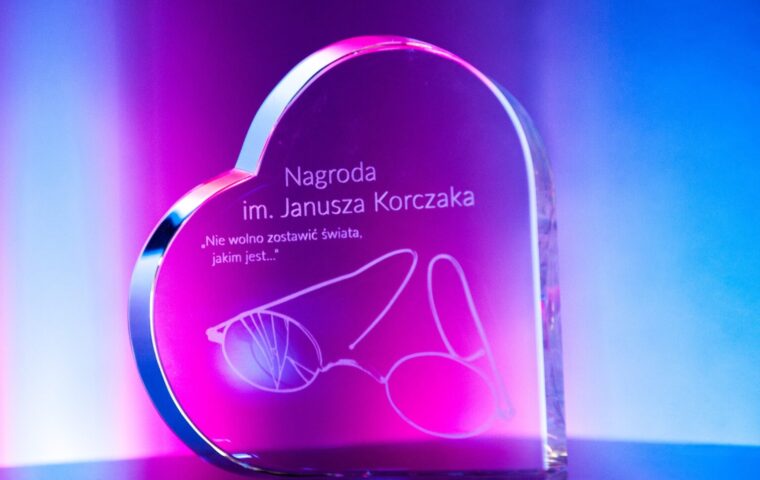 Statuetka w kształcie serca z napisem „Nagroda im. Janusza Korczaka” na kolorowym tle