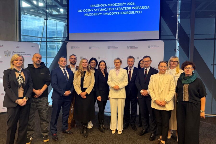 Grupa osób stojąca przed ekranem z prezentacją podczas konferencji o diagnozie młodzieży 2026