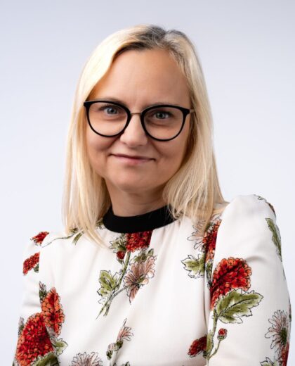 Portret kobiety w okularach i jasnej bluzce w kwiatowy wzór na jasnym tle