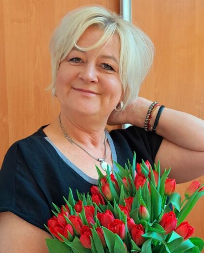Portret kobiety trzymającej bukiet czerwonych tulipanów na tle drewnianych drzwi