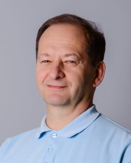 Portret mężczyzny w jasnoniebieskiej koszulce polo na jasnym tle.