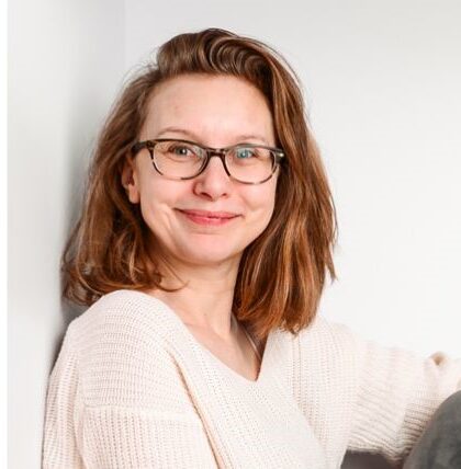 Portret kobiety w okularach i jasnym swetrze na jasnym tle