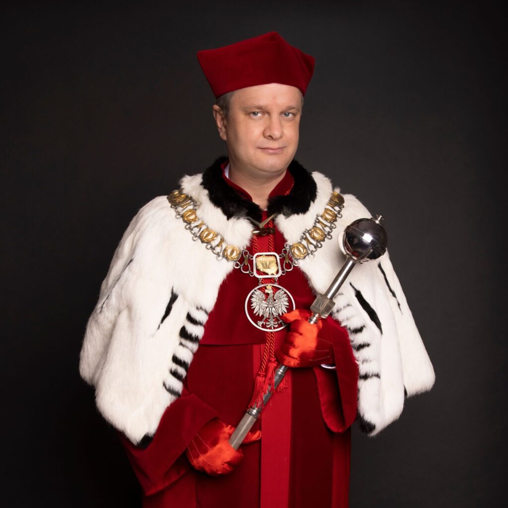 Portret mężczyzny w czerwonej todze rektorskiej z białym futrzanym kołnierzem i biretem, trzymającego berło. Na szyi ma łańcuch z godłem Polski, a jego twarz jest skierowana w stronę widza.
