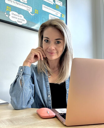 Portret kobiety siedzącej przy laptopie w biurze, z plakatem na ścianie w tle