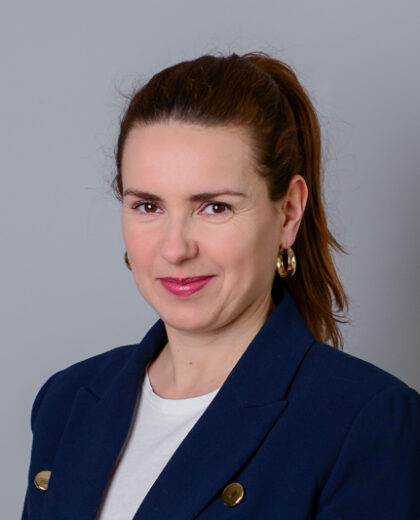 Portret kobiety w granatowej marynarce na jasnoszarym tle