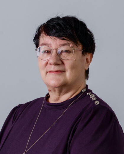 Portret kobiety w okularach i fioletowej bluzce na jasnoszarym tle