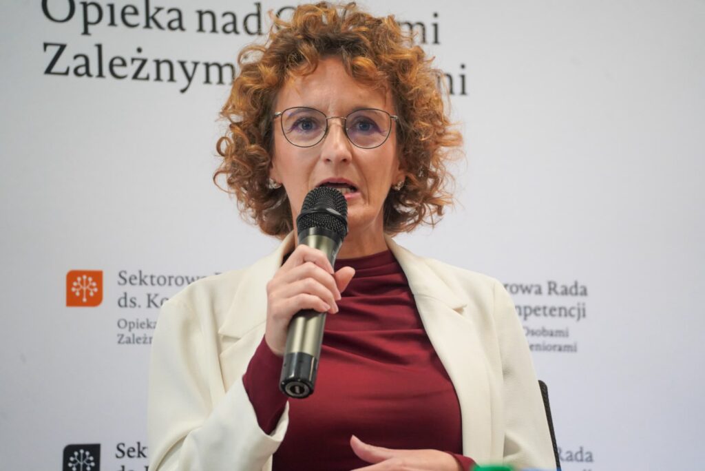Ekspertka dr Justyna Hołyst w białej marynarce i bordowej bluzce wypowiada się podczas debaty CARESKILLS TALKS 3